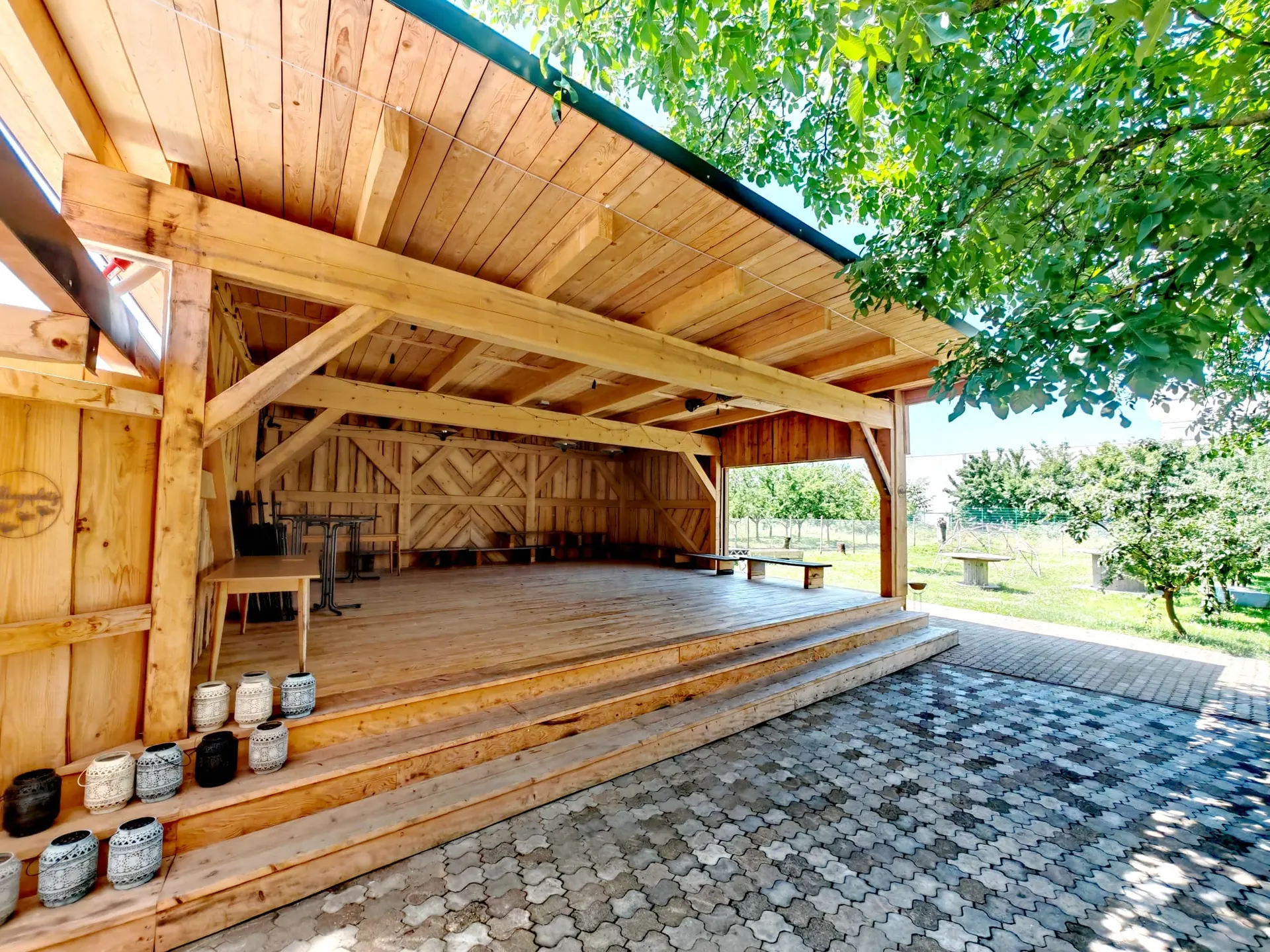 Überdachte Holzbühne mit offenem Blick in die Streuobstwiese